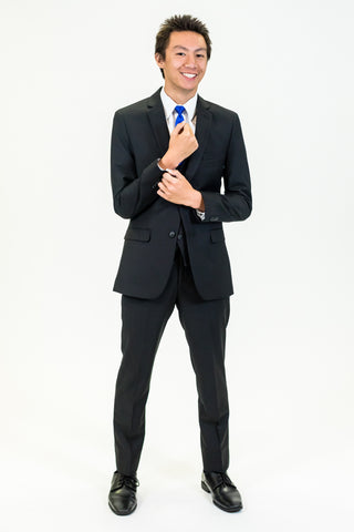 high school student boy wearing black suit blue tie standing adjusting left cuff