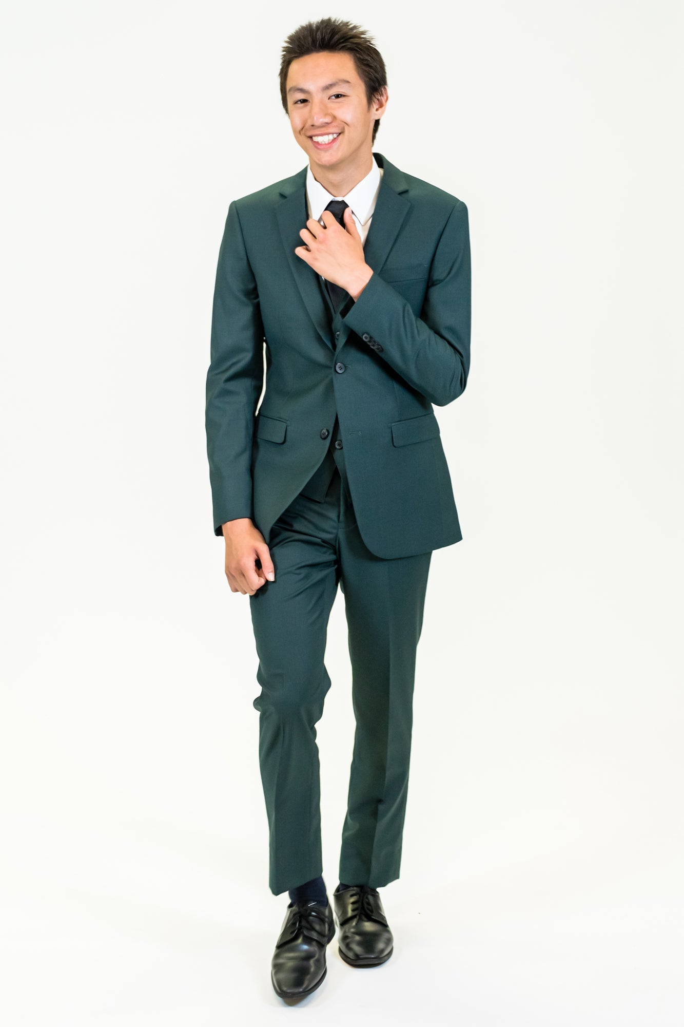 high school student boy wearing green suit walking adjusting black tie