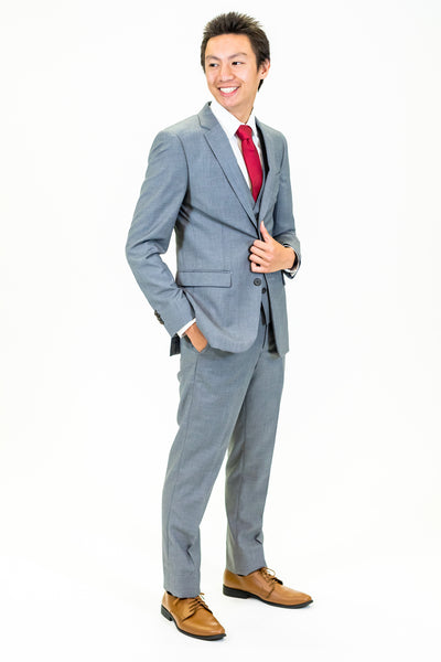 high school student boy wearing grey suit red tie standing hand in left pocket facing left